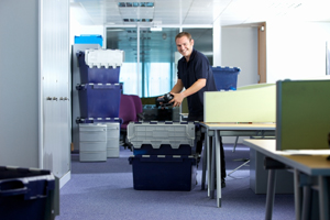 A cheerful looking removal man loading up delivery crates. office moves